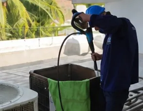 Técnico lavando una condensadora con hidrolavadora